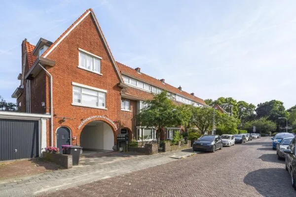 Rij stijlvol gerenoveerde jaren-'30 woningen aan de Jacques Perkstraat met zicht op Ondernemersplein De Regenboog.